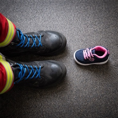 Einsatzstiefel des Rettungsdienstes neben einem kleinen Kinderschuh